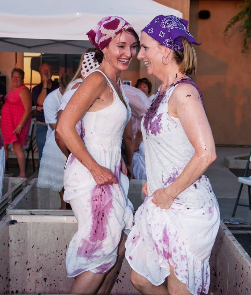 women stomping grapes wearing white dresses and bandanas