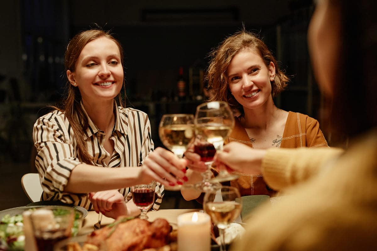 people sitting around table with wine glasses and food